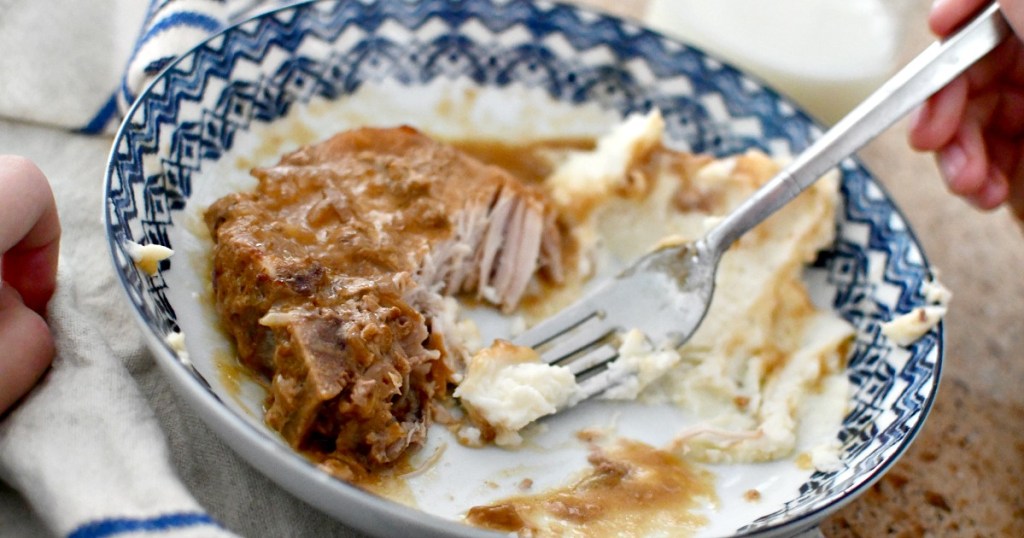 eating pork chops and mashed potatoes on a plate