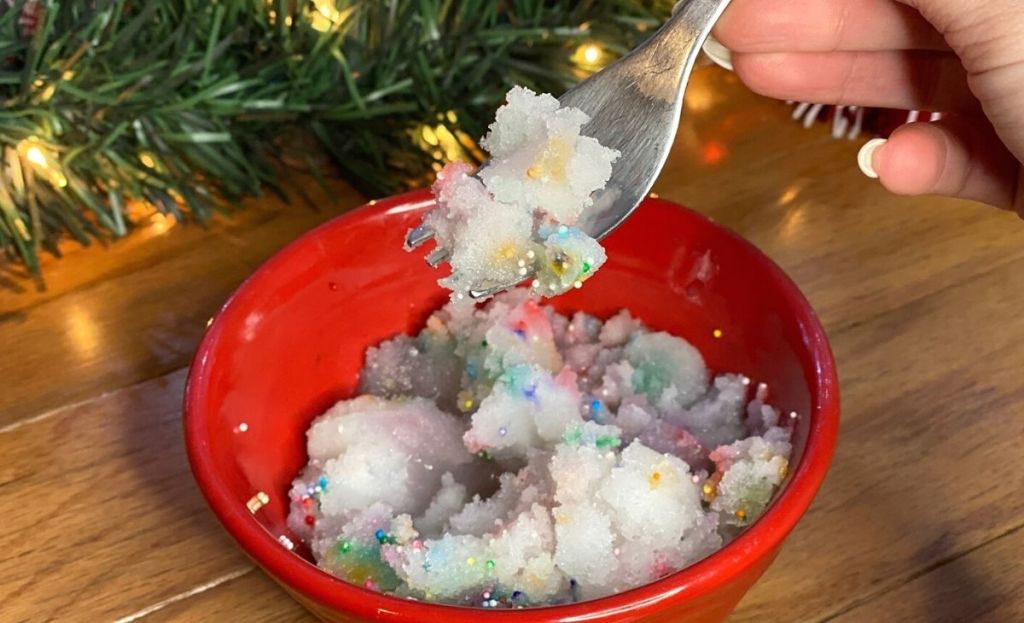 A hand holding a bite of ice cream over a bowl