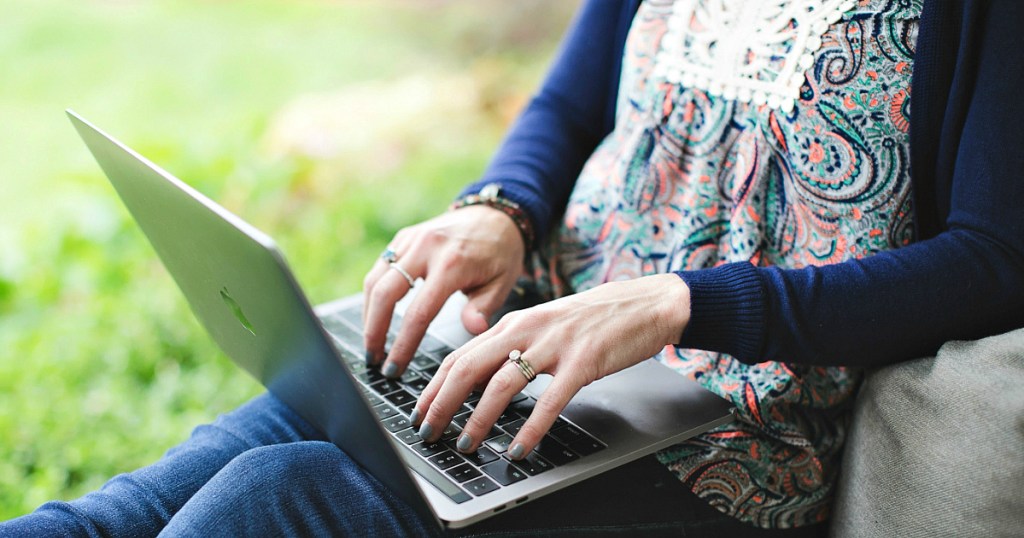 woman typing on macbook outside
