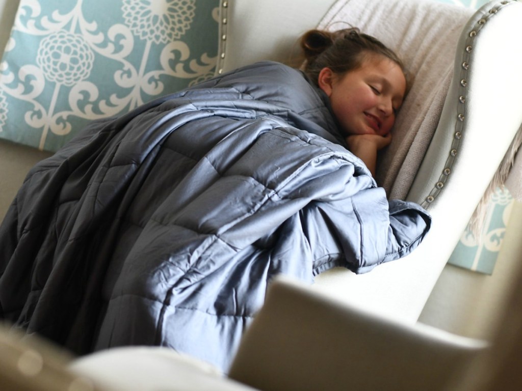 girl laying on chair with weighted blanket