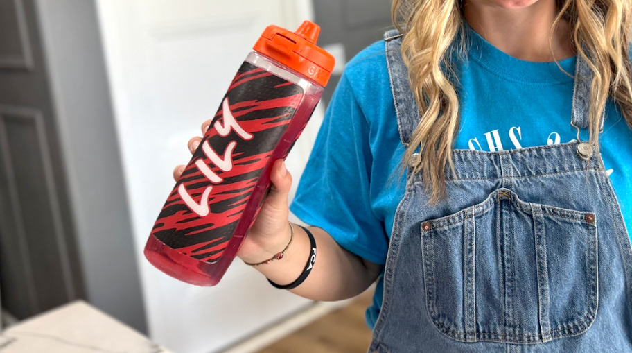 a teen girl holding a personalized red and black print Gatorade plastic water bottle