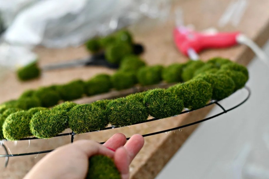 hand holding the edge of the moss wreath on counter