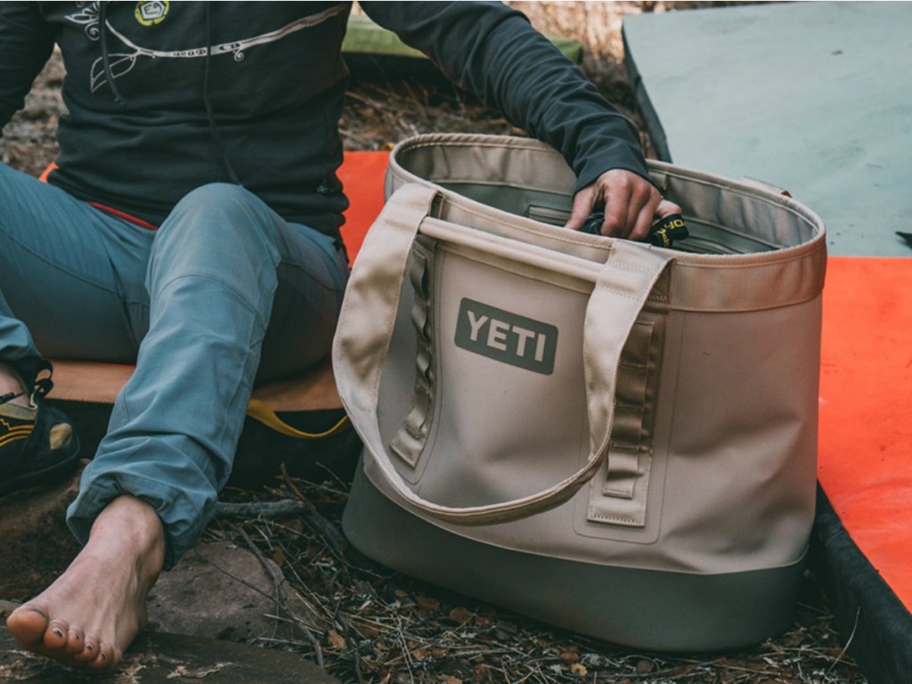man sitting next to a yeti camino tote outside