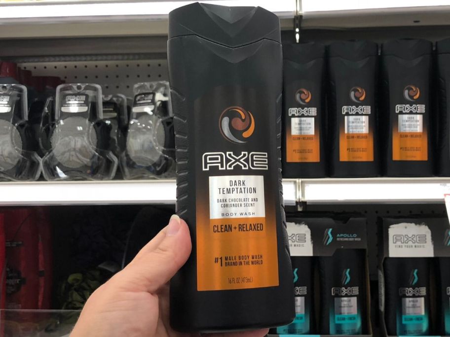 woman's hand holding bottle of body wash in front of store shelf