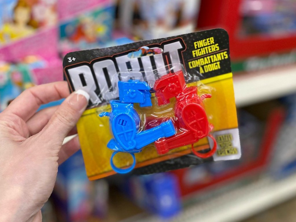hand holding little package of toy robots by store display