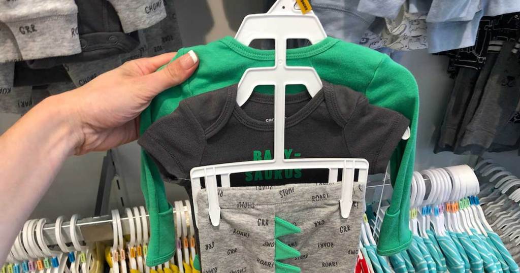woman's hand holding 3-piece dinosaur carter's set