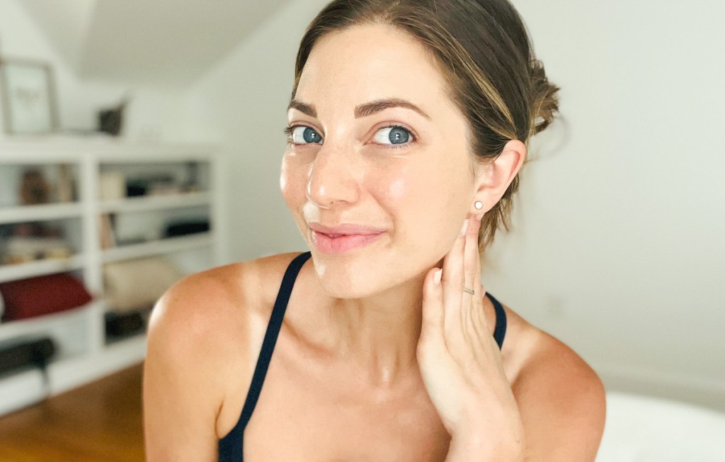 woman holding neck showing off glowing face before and after lymphatic drainage massage