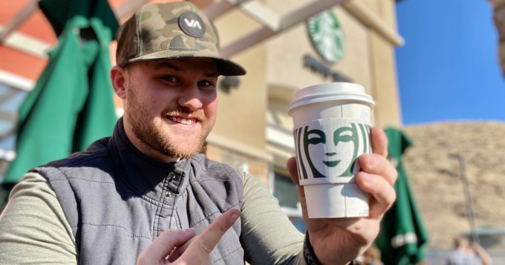 man holding hot starbucks drink outside