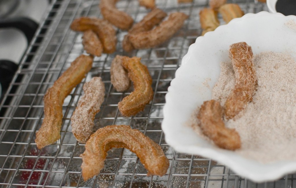 rolling churros in sugar and cinnamon