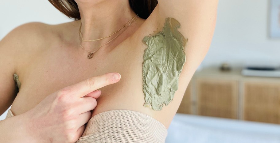 finger pointing to armpit with green clay