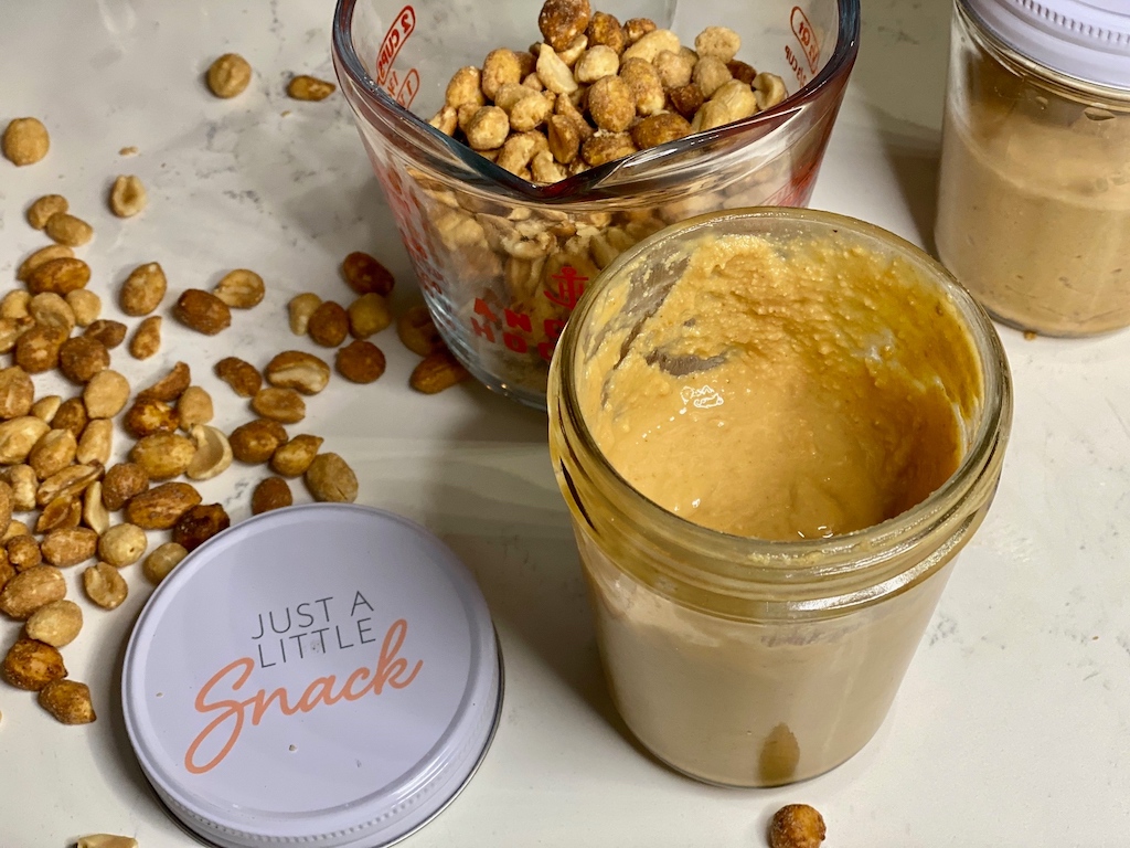 homemade peanut butter in jar and peanuts in measuring cup 