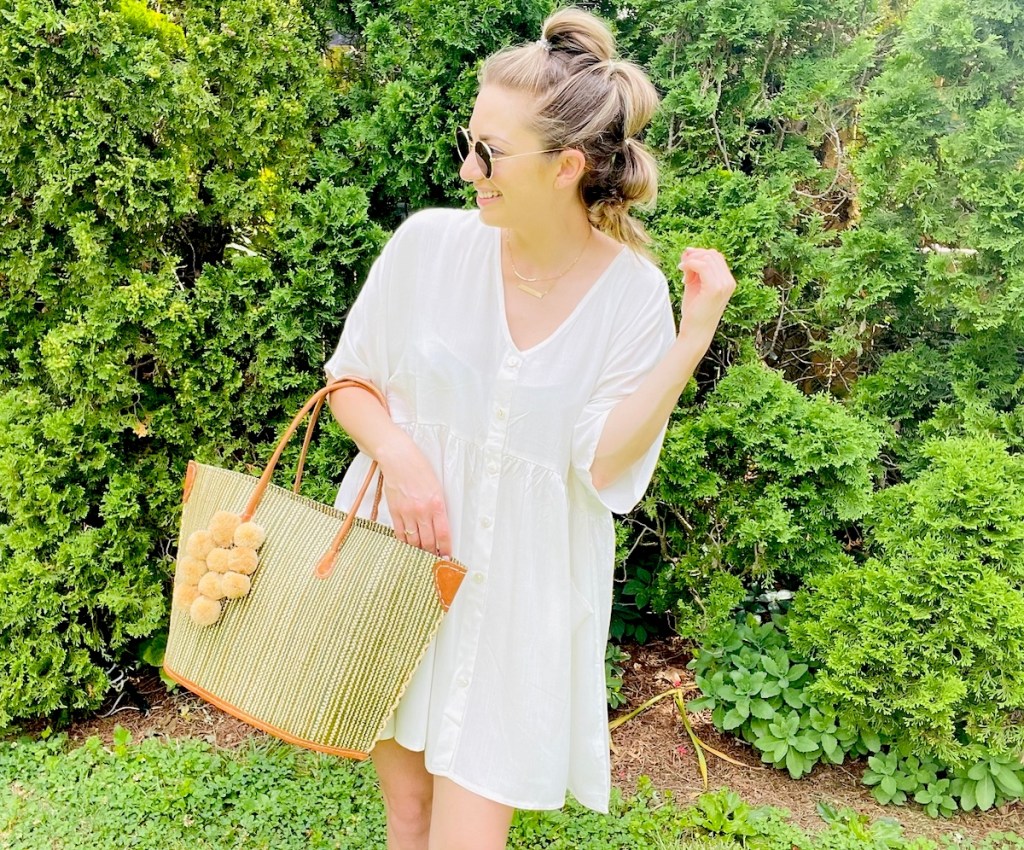 woman wearing white dress holding beach bag outside