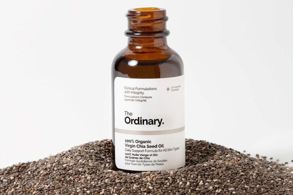 Chia seed oil in a bottle sitting on top of chia seeds