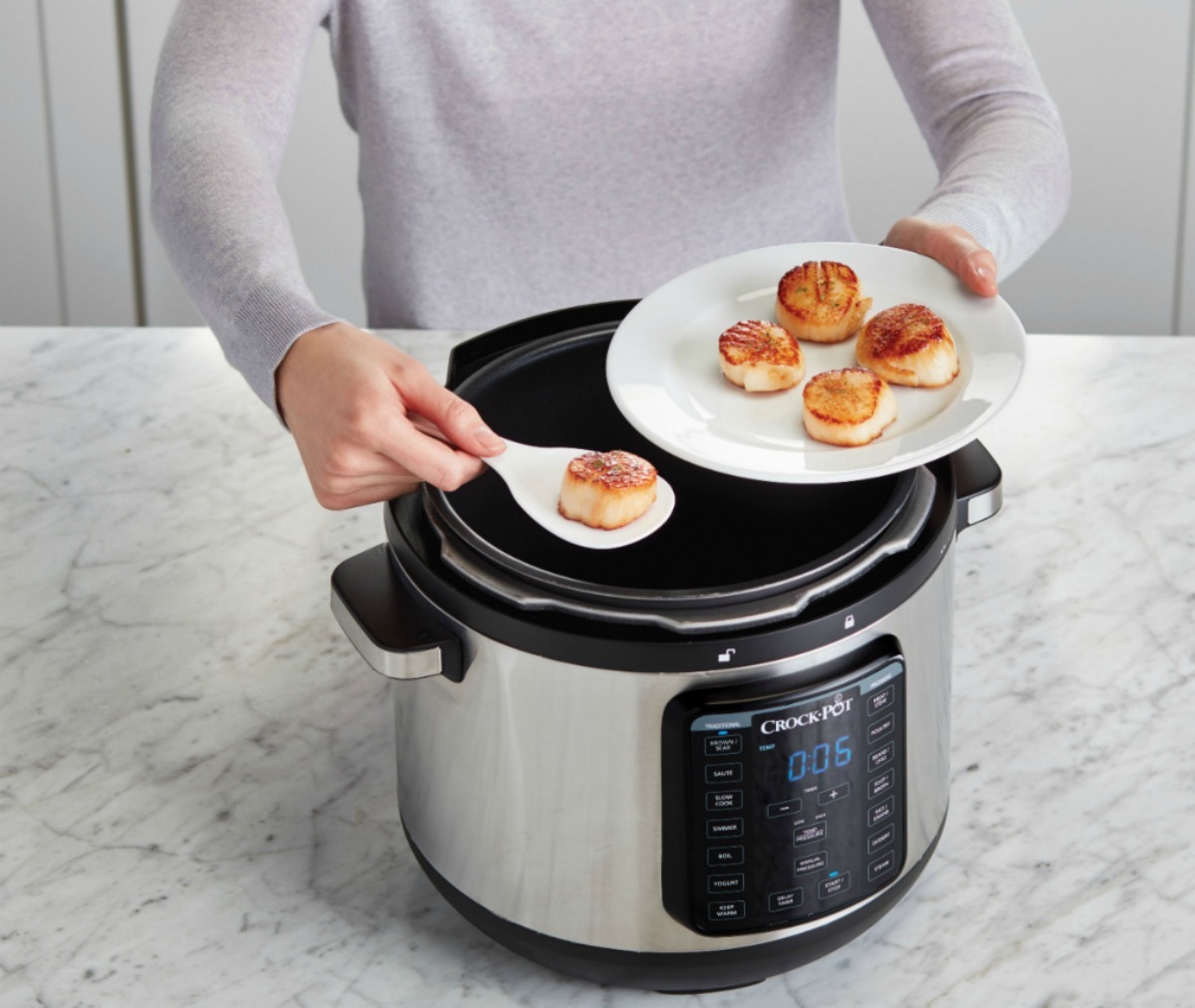 Woman dishing up plate of scallops from pressure cooker on counter top