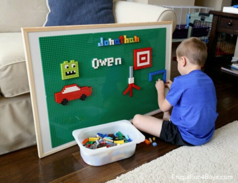 boy adding Lego pieces to vertical play surface