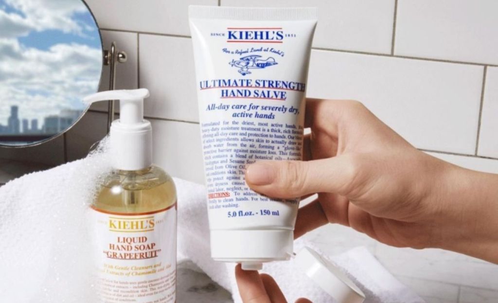 A hand squeezing hand salve into the other hand in a bathroom