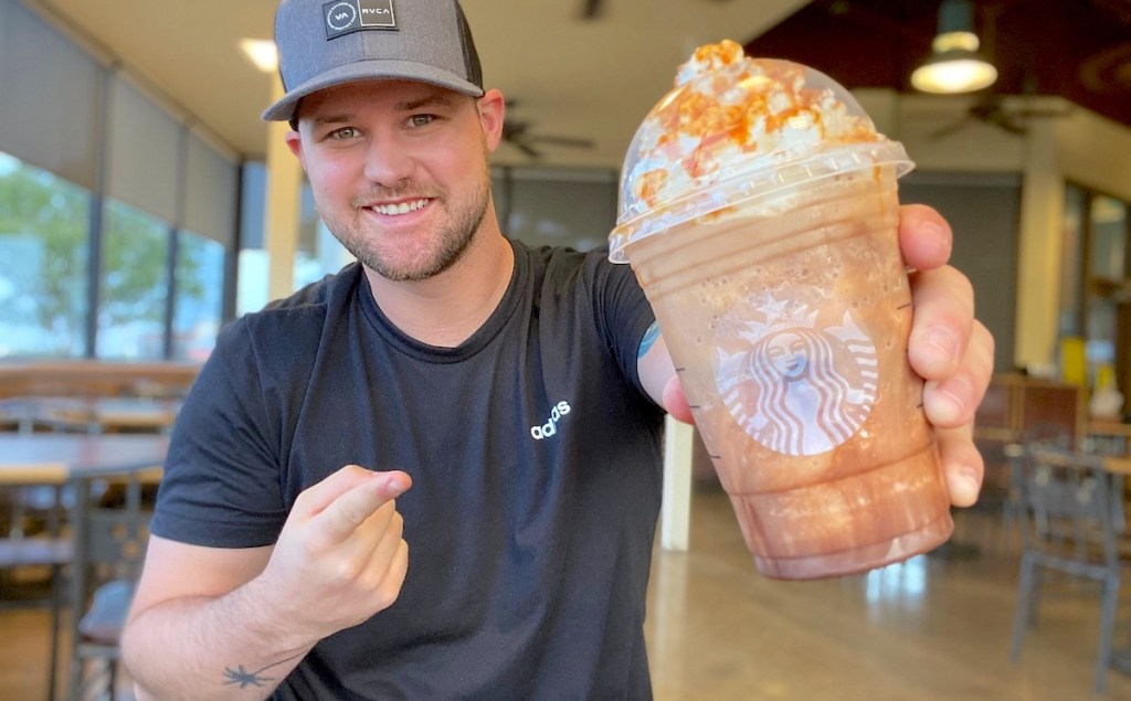 man holding a chocolate pumpkin frapp in starbucks store