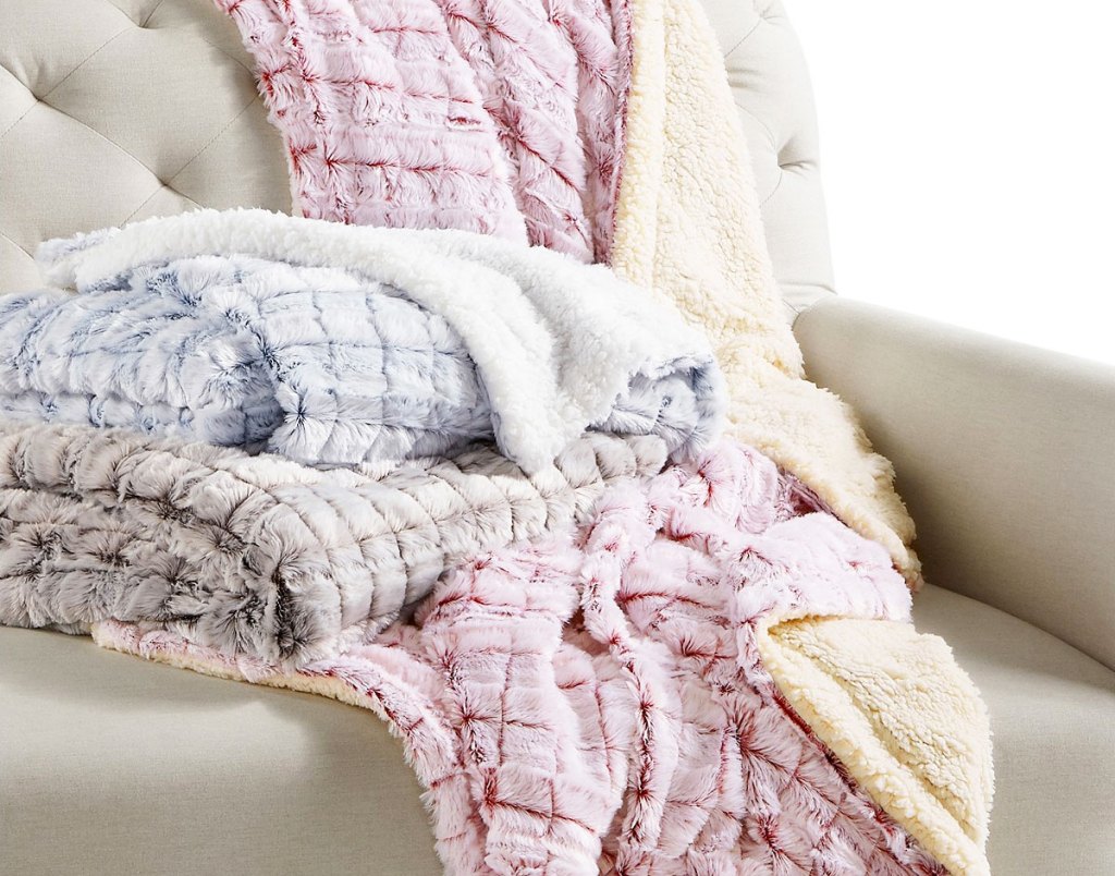 red, blue, and black reversible mink and sharpe throws piled on a cream couch