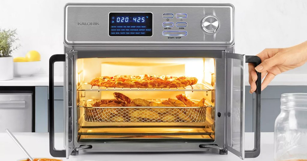 stainless steel air fryer oven on kitchen counter with french doors opened showing racks of food cooking inside