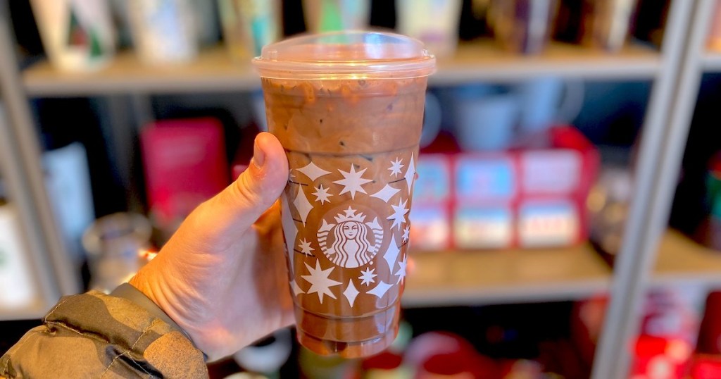 hand holding out starbucks cups with hot cocoa cold brew inside