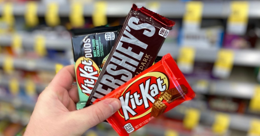 hand holding 3 hershey's candy bars at walgreens