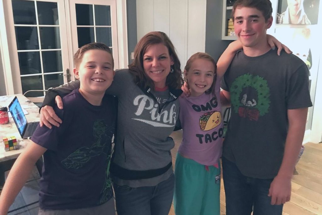 A woman and three children in a kitchen smiling