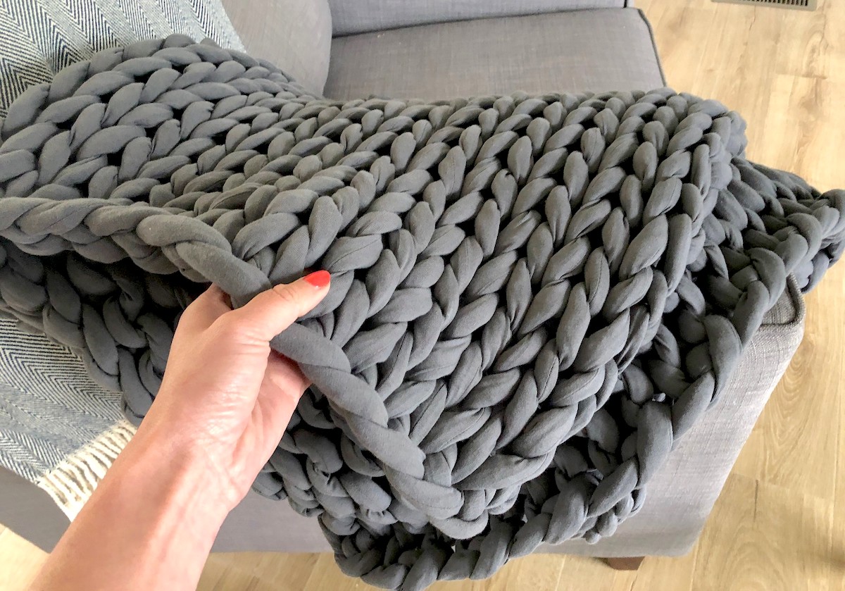 hand holding corner of gray bearaby weighted blanket