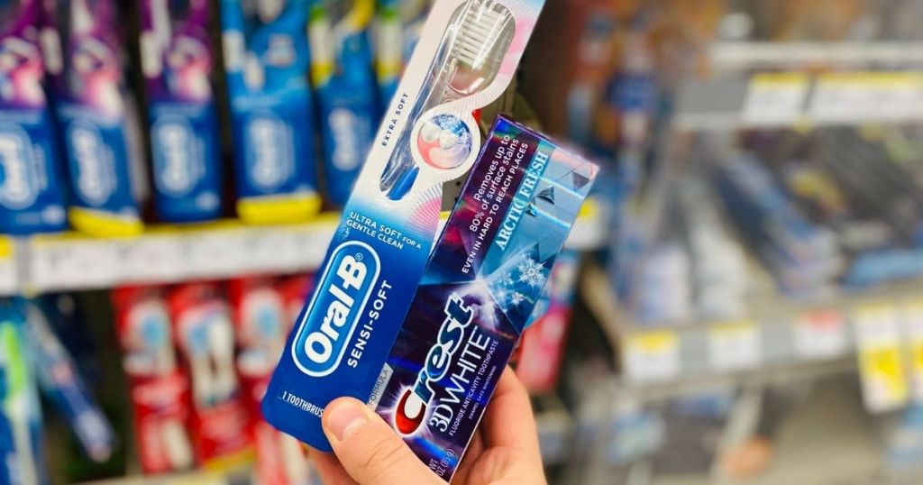 hand holding Crest Toothpaste and an Oral-B Toothbrush
