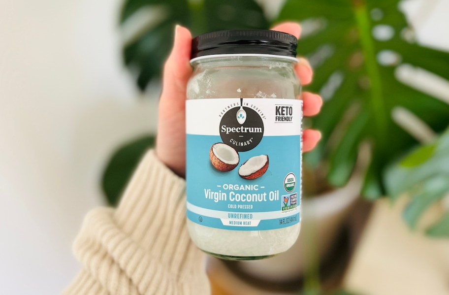 hand holding a glass bottle of coconut oil