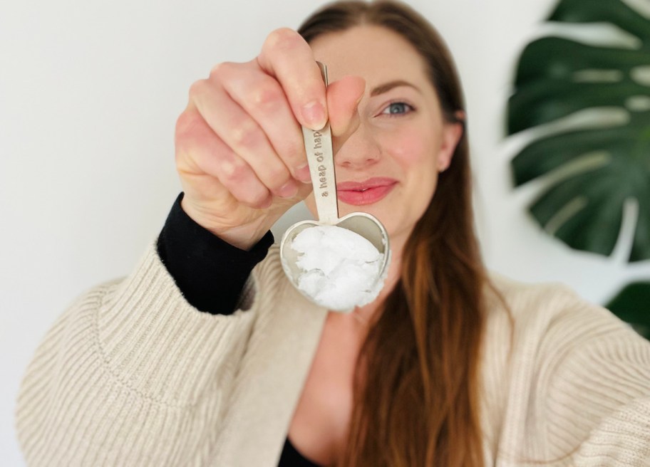 woman holding spoonful of coconut oil