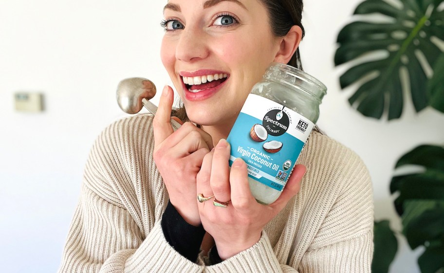 woman holding bottle of coconut oil smiling