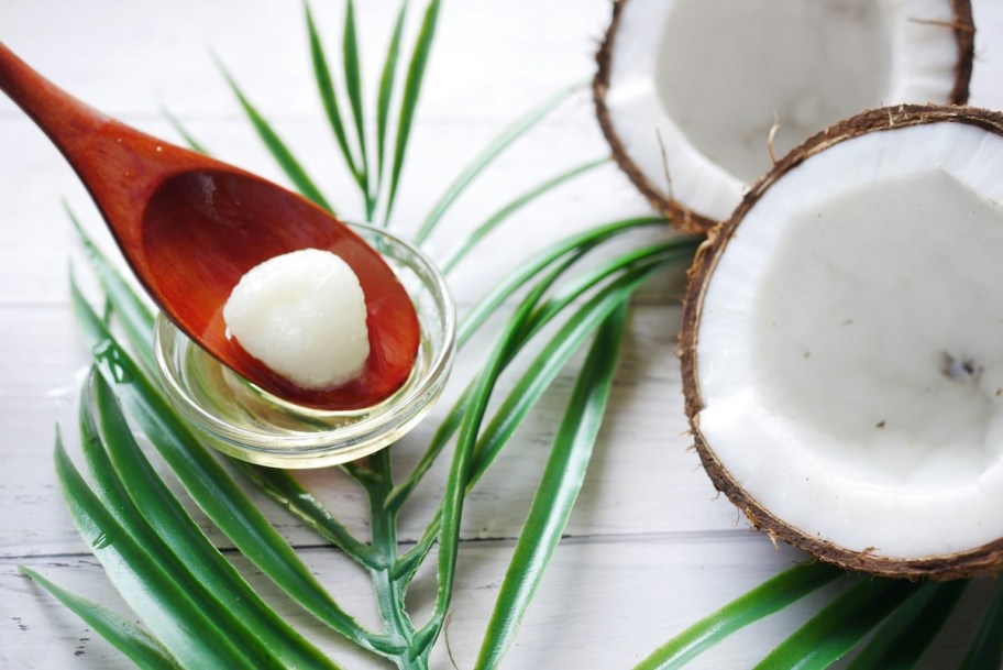 open coconut with wooden spoon in bowl with oil