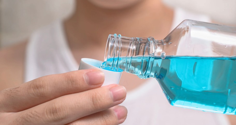 pouring blue mouthwash into white cap
