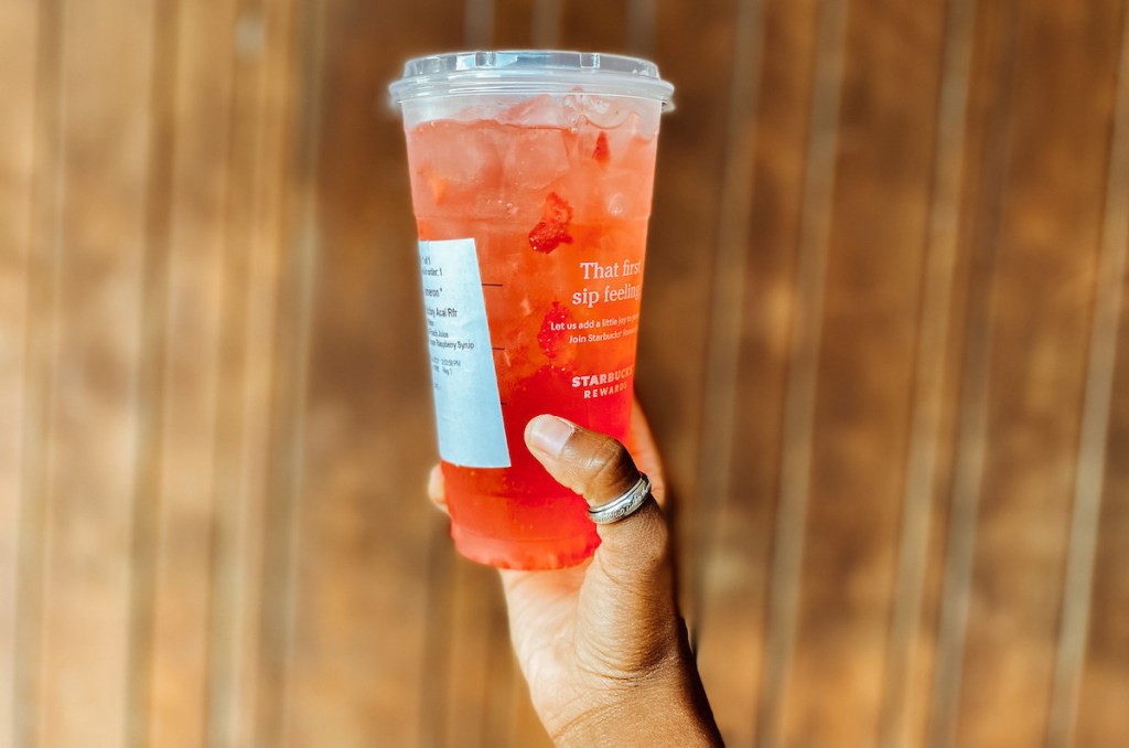 hand holding starbucks gummy bear secret menu drink in front of wooden wall