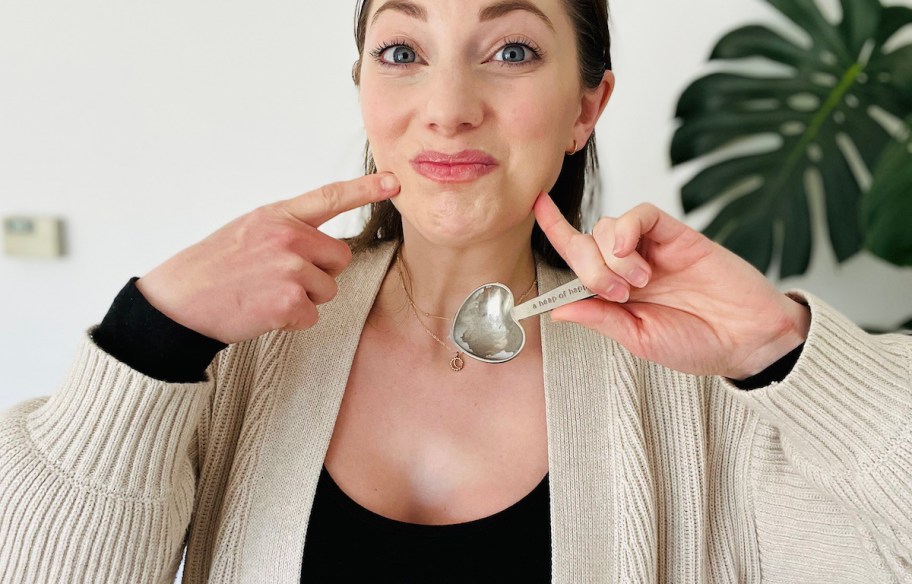 woman pointing to face holding measuring spoon