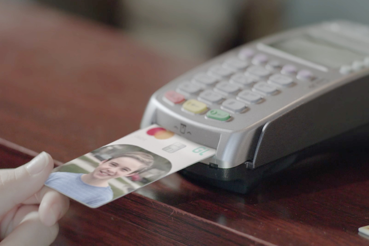 Person swiping the Greenlight debit card for kids