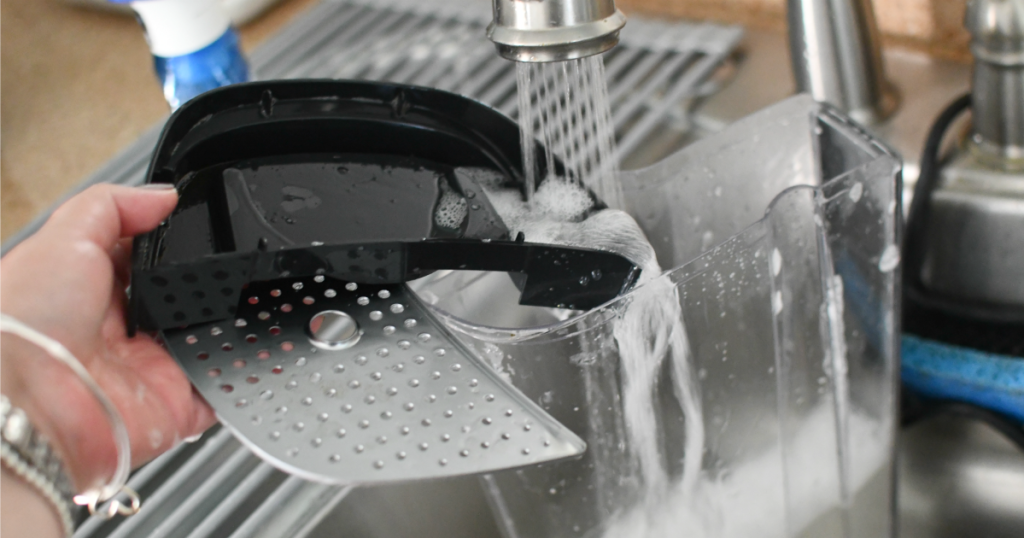 rinsing out the top of a keurig maker to clean out coffee machine