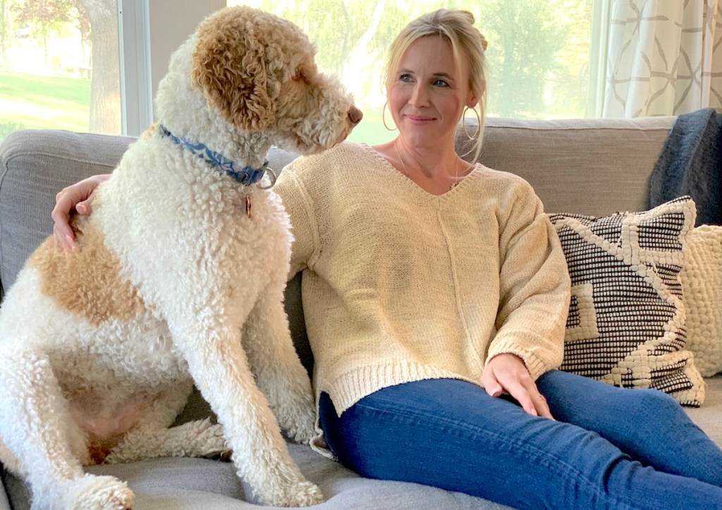 woman and dog sitting on couch in front of large window