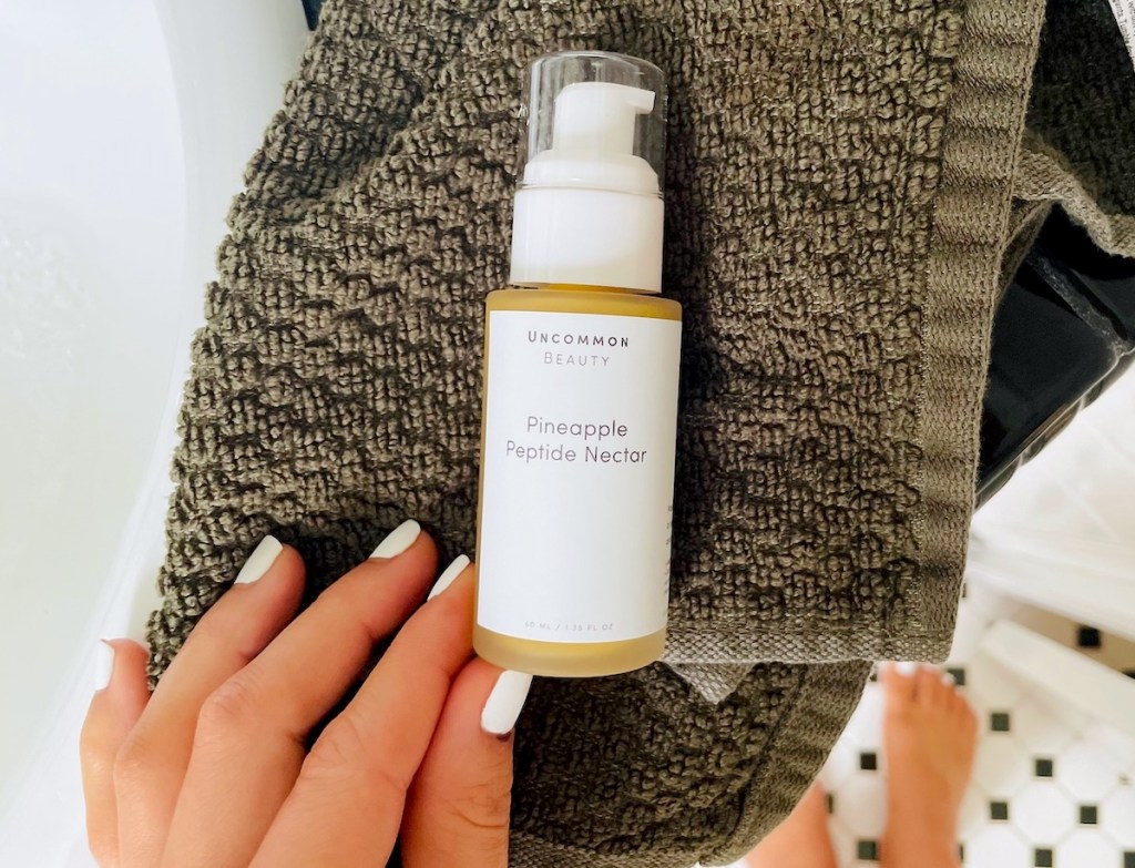 hand holding corner of pineapple peptide nectar serum in bathroom