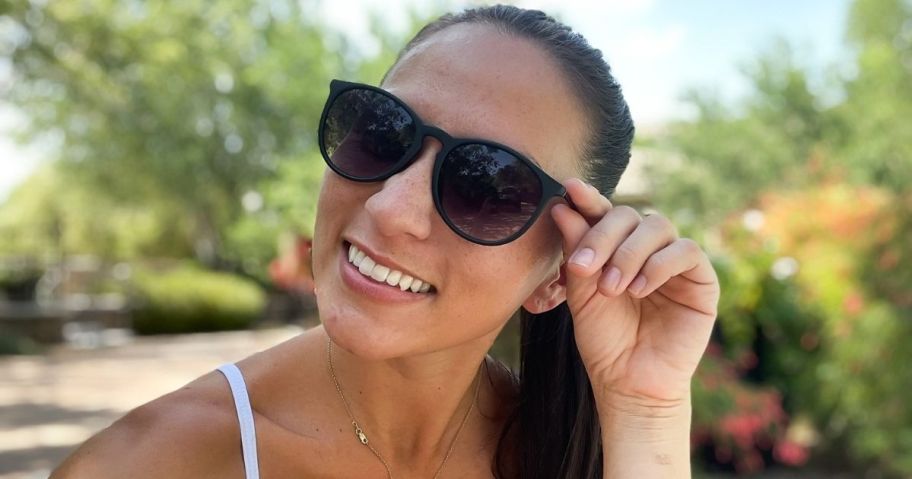 woman smiling at the camera wearing sunglasses