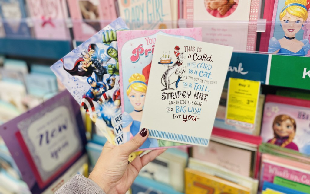 hand holding three birthday cards in hallmark store aisle