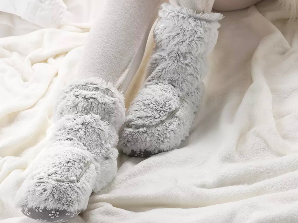 gray warmies boots on feet on bed