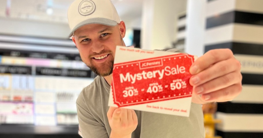 man holding up JCPenney Mystery Coupon