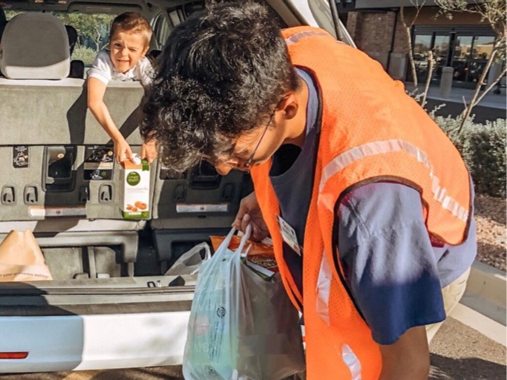 child watching man load groceries into back of car