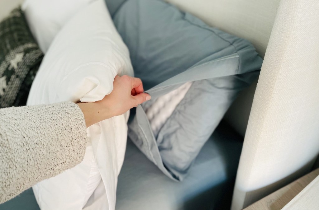 hand pulling back blue pillowcase on bed