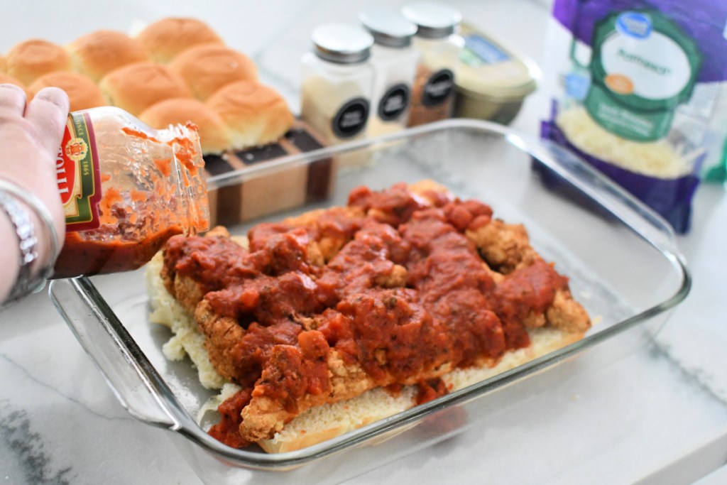 pouring marinara sauce over chicken tenders
