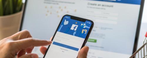 facebook login page on phone and computer in background
