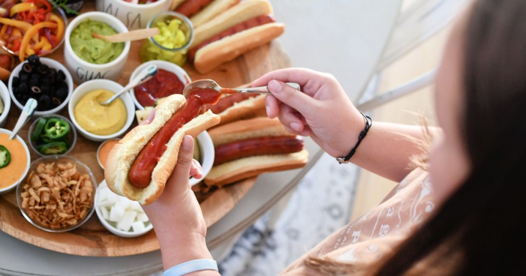 girl dishing up a hot dog with toppings