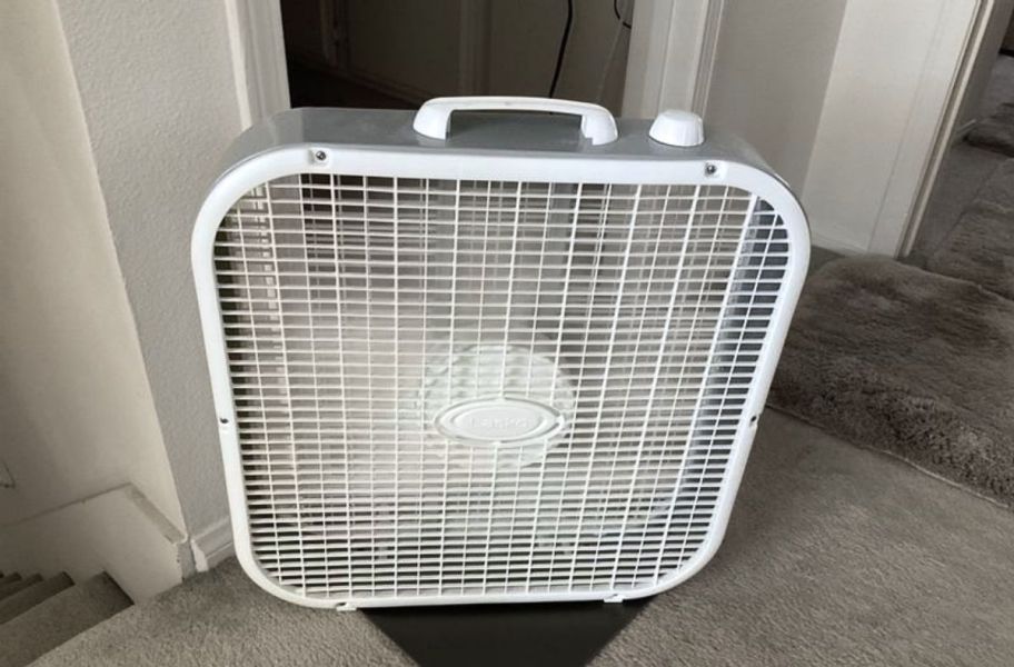 a white box fan sitting in front of a door on a stair landing