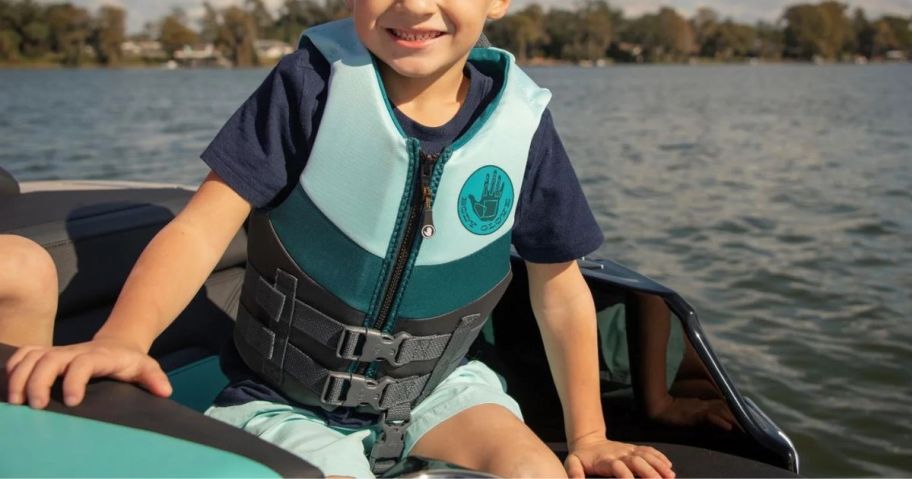 boy sitting on boat wearing Body Glove Life Jacket in blue